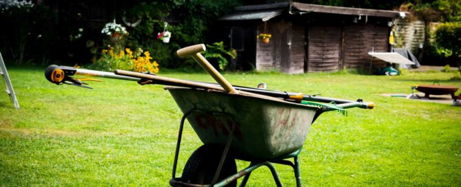Schubkarre mit verschiedenen Arbeitsgeräten in einem Garten
